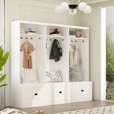 a white coat rack filled with clothes next to a large open window and potted plant