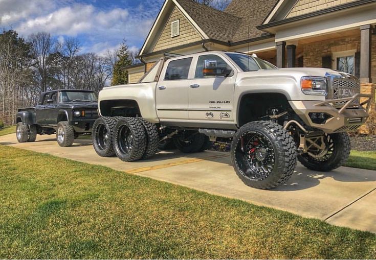 a white truck parked in front of a house next to a black jeep on a driveway