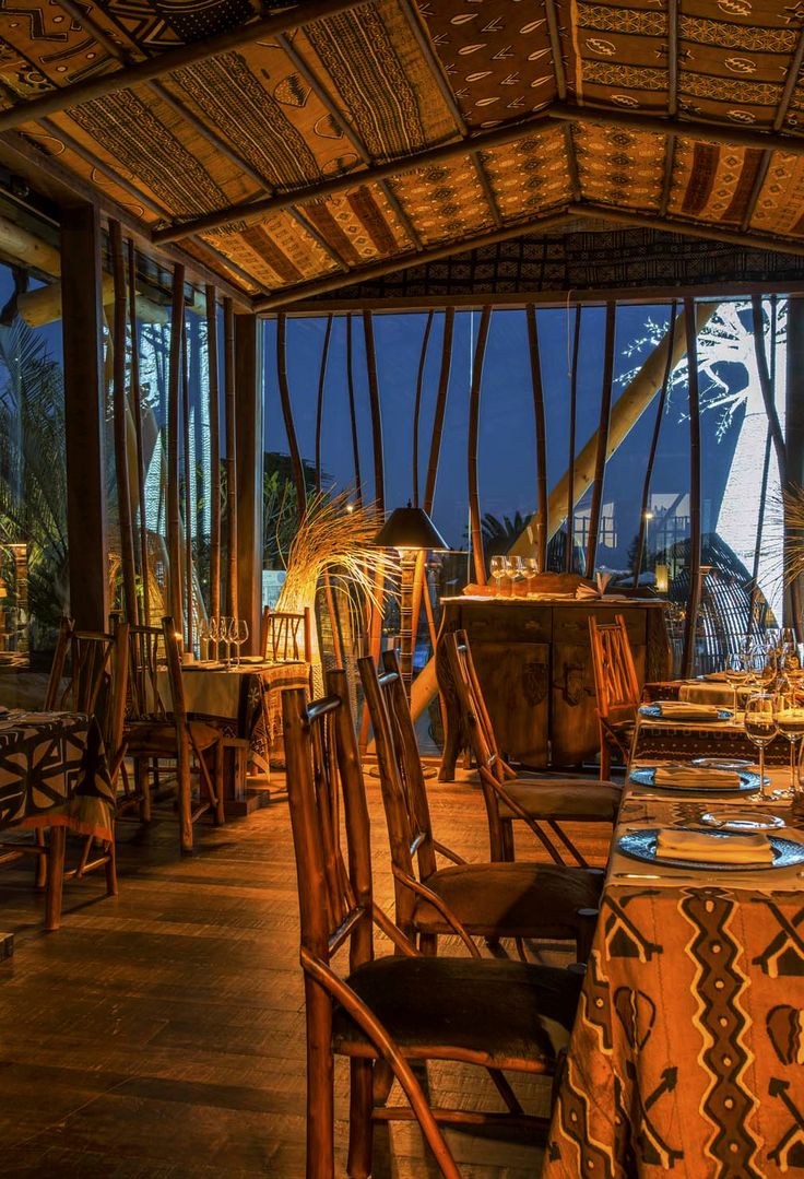 a restaurant with wooden tables and chairs in front of large windows overlooking the ocean at night