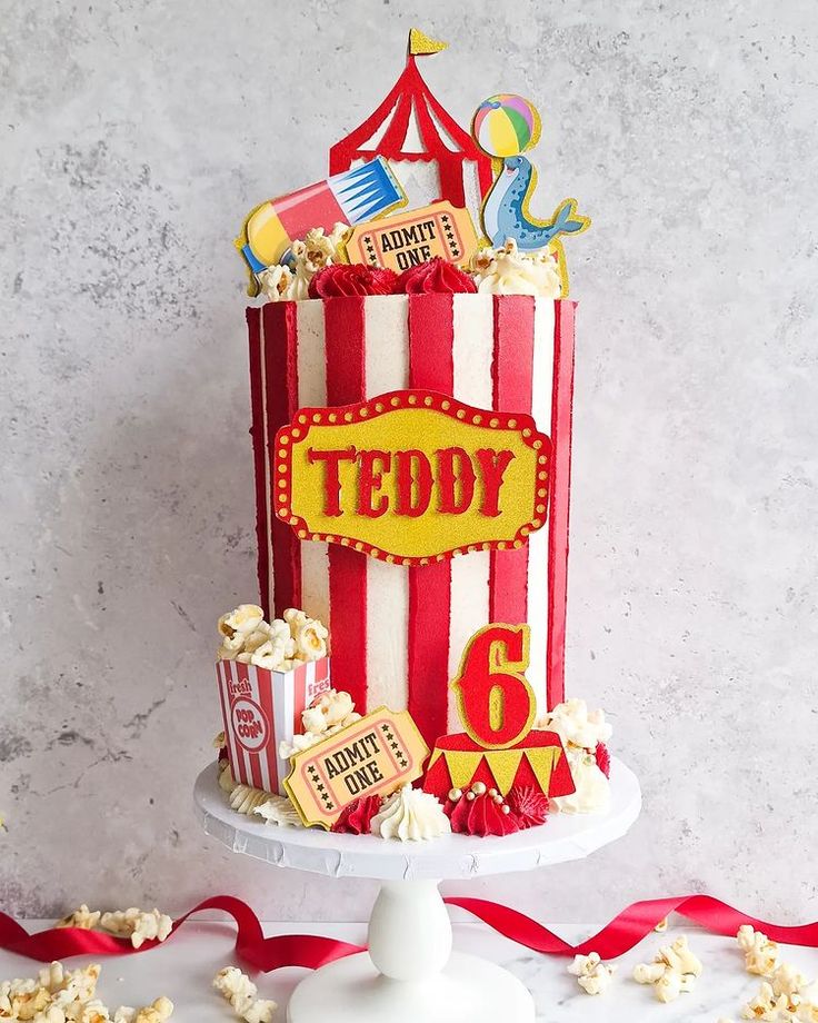 a red and white striped cake sitting on top of a table next to a popcorn bucket