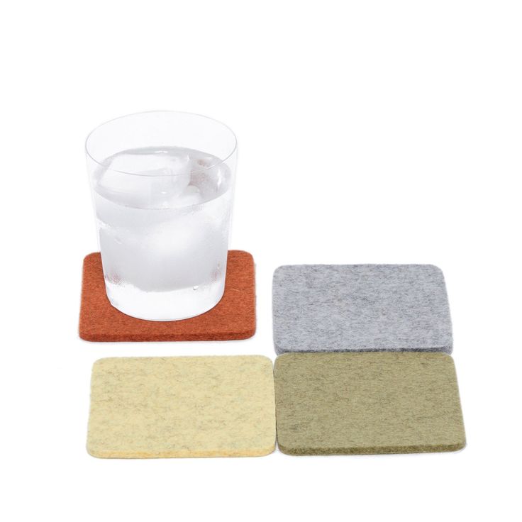 three different colored coasters next to a glass of water and ice on a white background