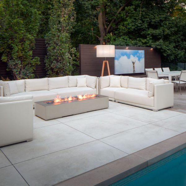 a large white couch sitting on top of a cement floor next to a swimming pool