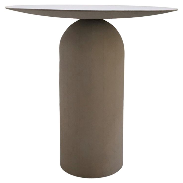 a round table with a white top sitting on a white surface, it is made out of concrete