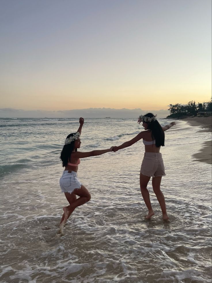 two women are playing in the water at the beach while one holds her hand out