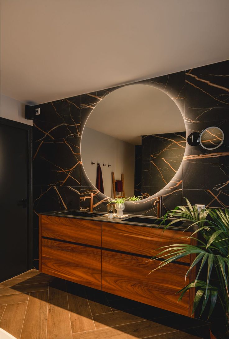 there is a mirror on the wall in this bathroom with wood flooring and black walls