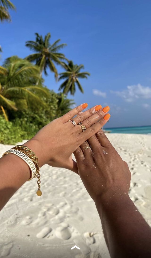 two hands holding each other on a beach with palm trees in the background and blue sky