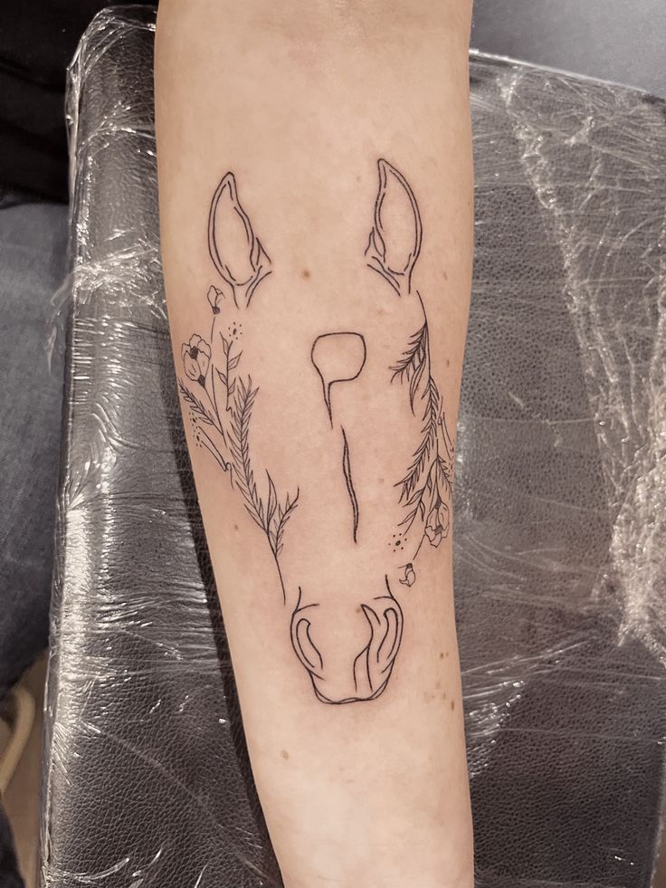 a tattoo on the leg of a person with a horse's head and flowers