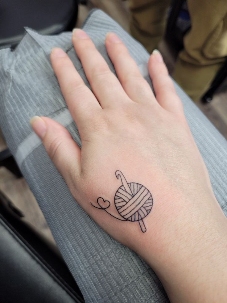 a woman's hand with a ball of yarn tattooed on it