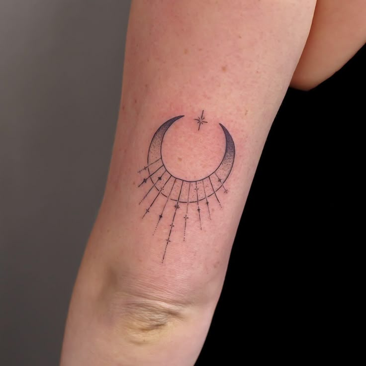 a woman's arm with a crescent and stars tattoo on the left side of her arm