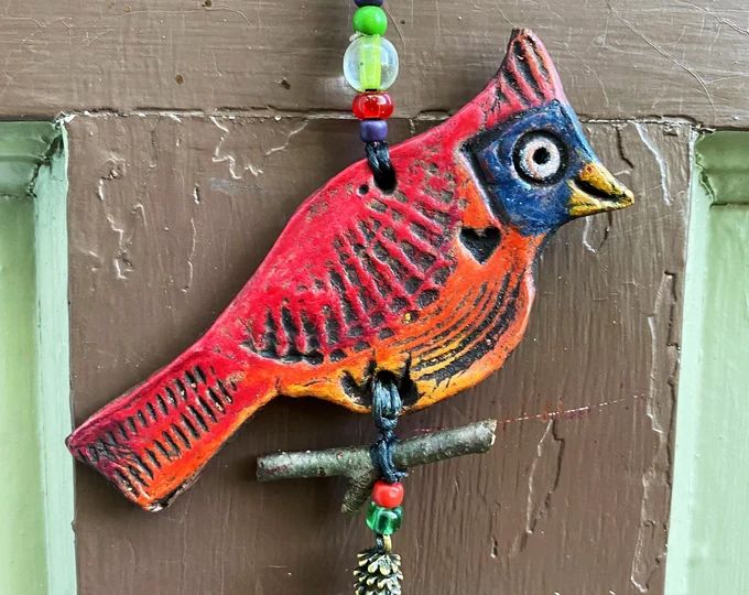 a colorful bird hanging on the side of a door with beaded necklaces around it's neck