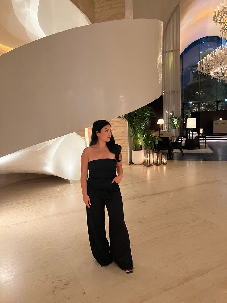 a woman is standing in the middle of a large room with chandelier hanging from the ceiling