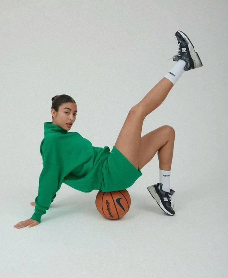 a woman in green is sitting on a basketball