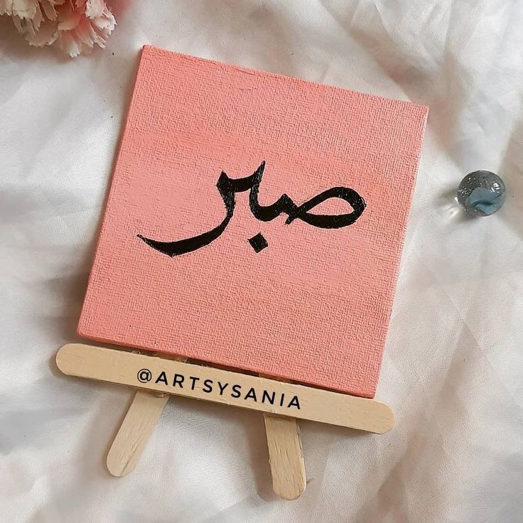 a pink book sitting on top of a white bed next to two small wooden clothes pins