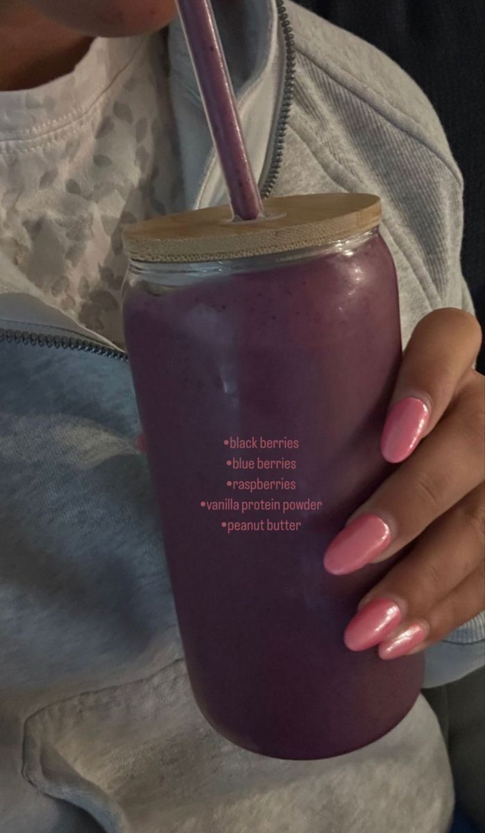 a woman holding a purple cup with a straw in it