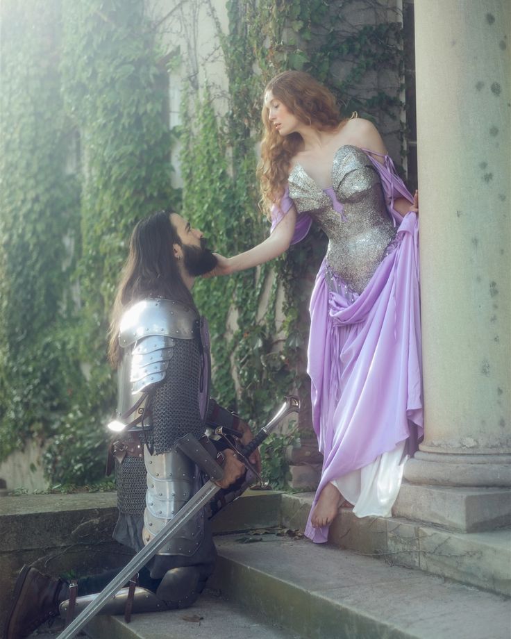 a woman in a purple dress standing next to a man in a knight costume on the steps