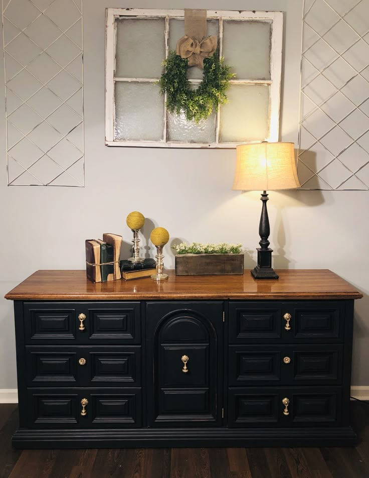 a black buffet with gold handles and knobs on the doors is next to a lamp