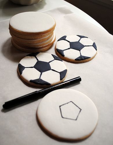 cookies decorated with black and white soccer balls are sitting on a table next to a marker