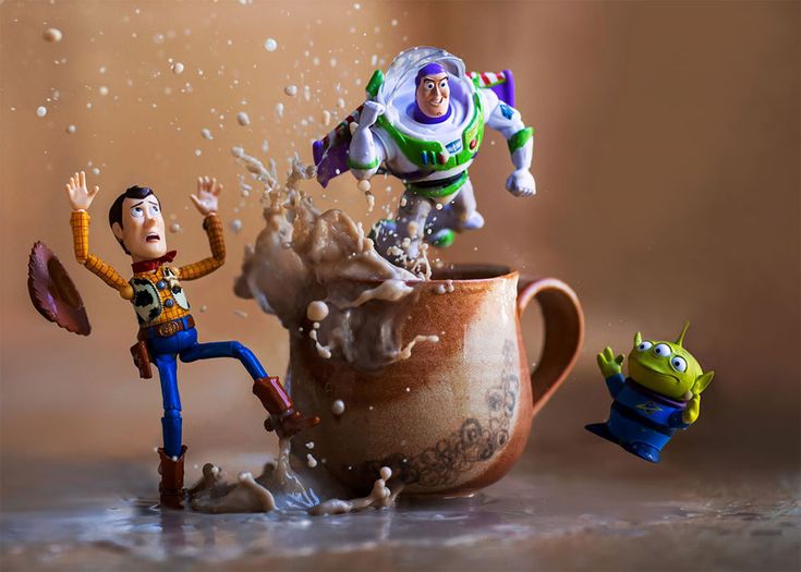 two toy figurines are splashing out of a coffee cup