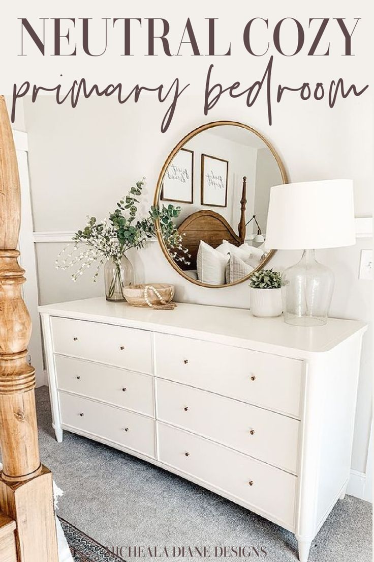 a white dresser with a round mirror on top and the words neutral cozy primary bedroom above it