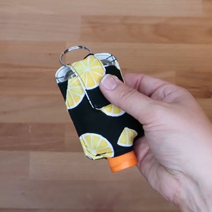 a hand holding an orange and black case on top of a wooden table next to a bottle opener