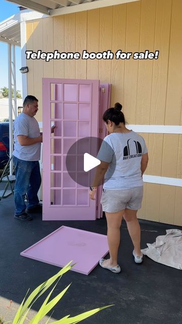 two people are standing in front of a pink door with the words telephone booth for sale