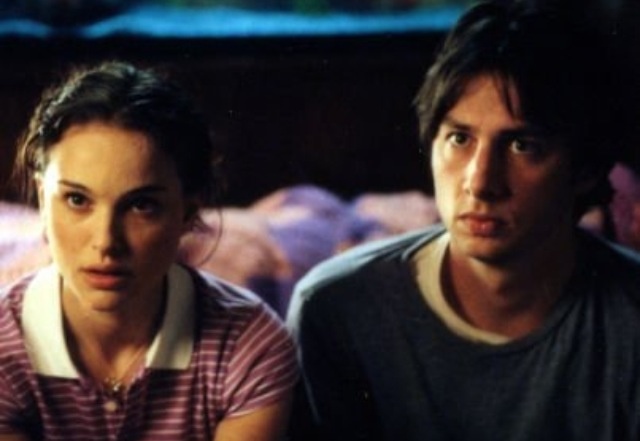 a young man and woman sitting on a bed looking at the camera with an aquarium in the background