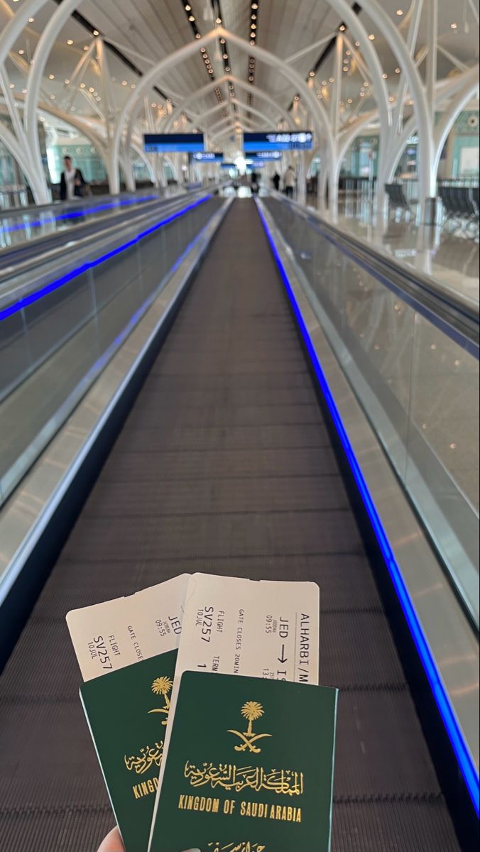 someone is holding up their passport in front of an escalator at the airport