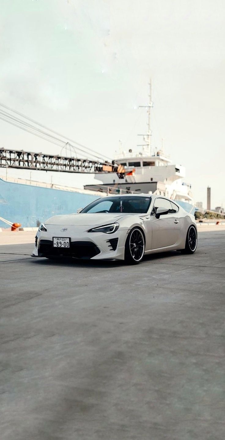 a white sports car parked in front of a boat