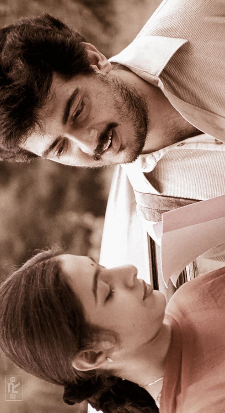 a man and woman standing next to each other in front of a tree with their eyes closed