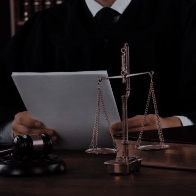 a judge sitting in front of a laptop computer next to a scale of justice