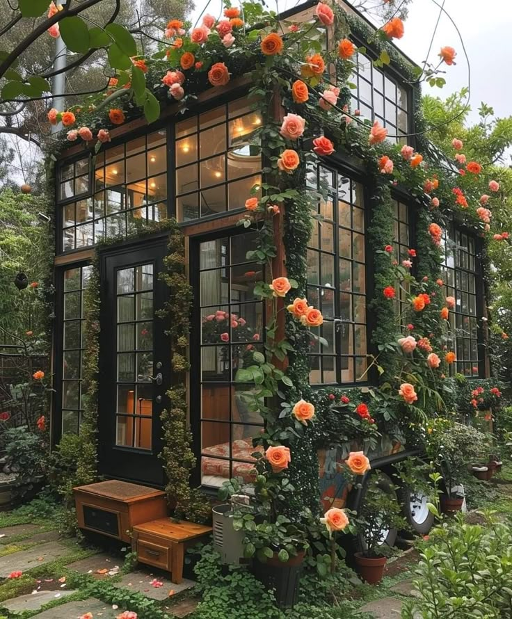 a small house covered in flowers and greenery