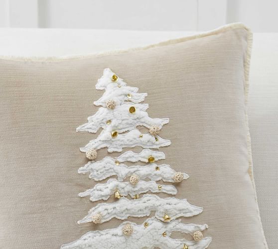 a white christmas tree pillow sitting on top of a couch