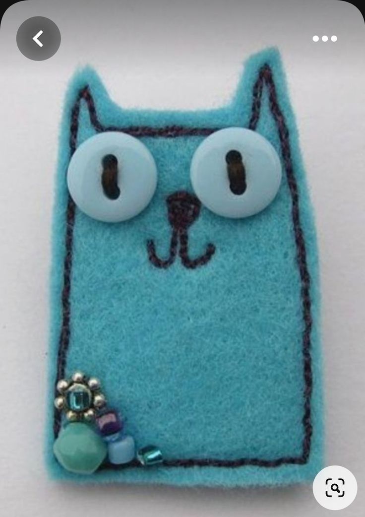 a blue cat brooch with eyes and beads on it