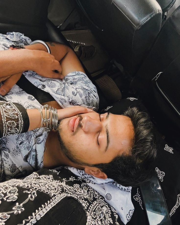 a man laying in the back seat of a car with his hand on his head