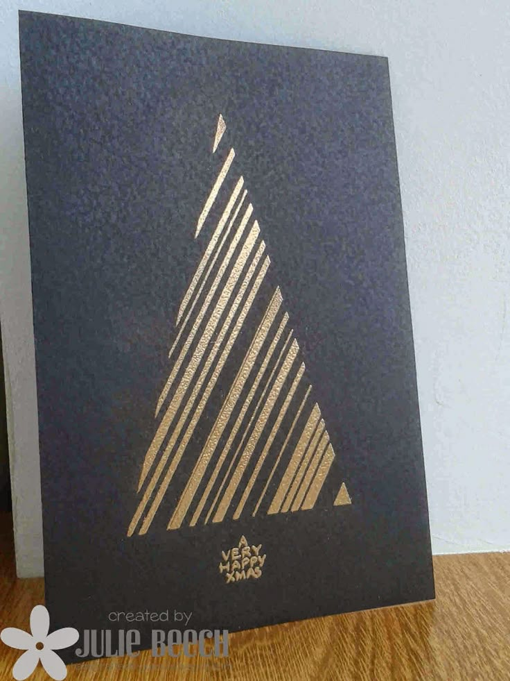 a black card with gold foiling on it sitting on a wooden table next to a white wall