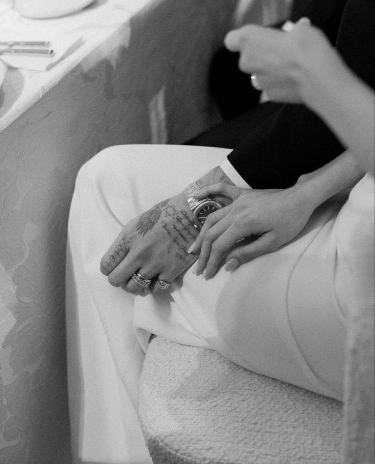 a woman sitting on a bed with her foot covered in tattoos and holding a magazine