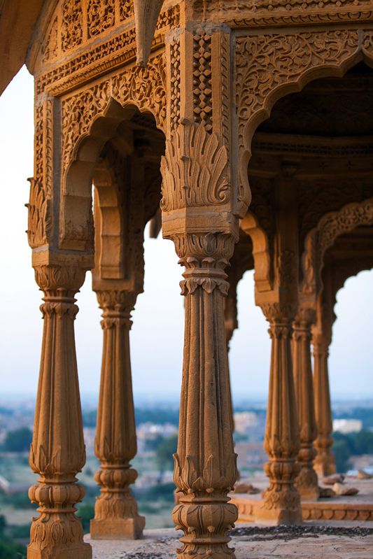 an intricately carved wooden structure with columns and pillars in the foreground, overlooking a city