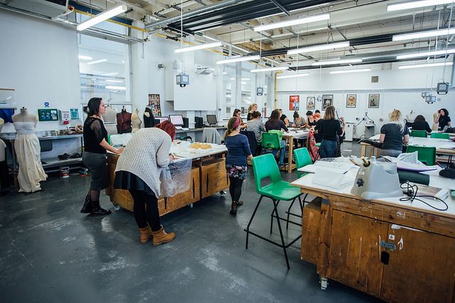 a group of people working in a large room with lots of desks and chairs