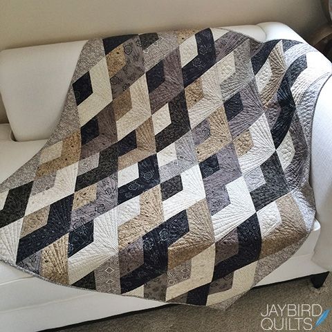 a white couch with a black and tan quilt on it