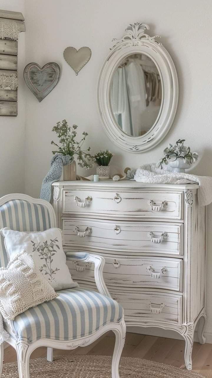 a white dresser sitting next to a chair in a room with heart shaped mirrors on the wall