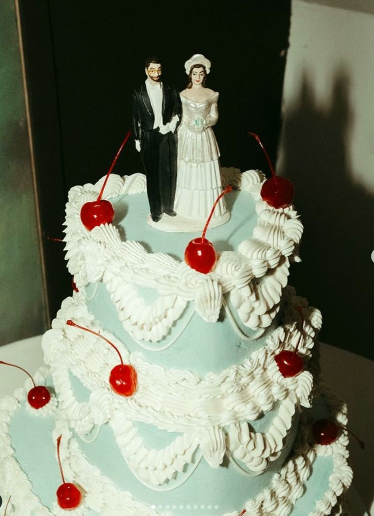 a wedding cake with cherries on it and a bride and groom figurine