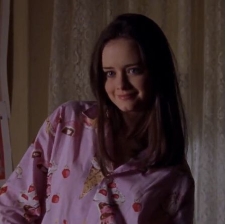 a woman wearing a pink shirt and tie standing in front of curtains