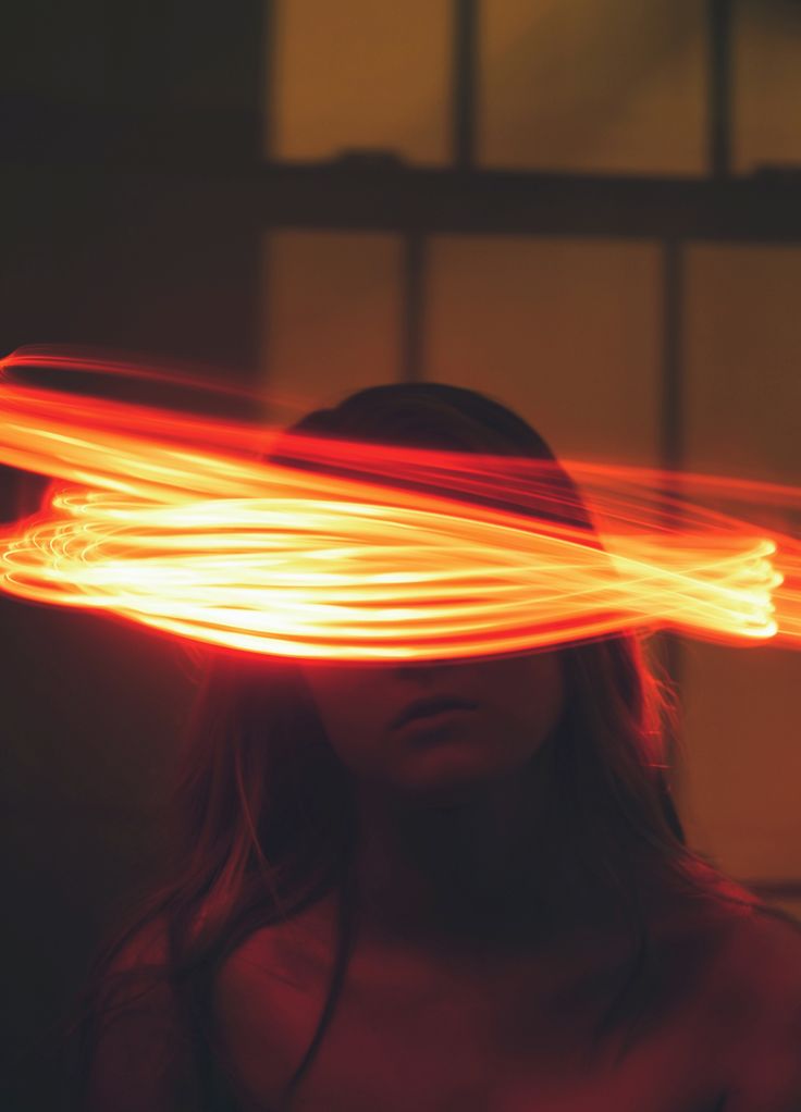 a woman wearing a hat with light streaks in front of her face and hair blowing through the air