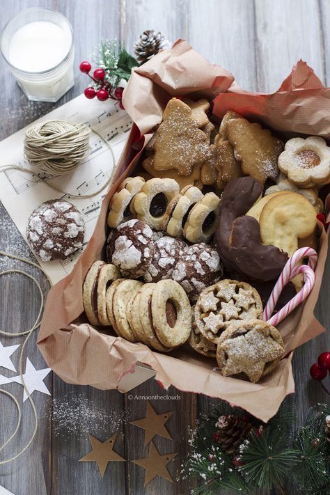 an assortment of cookies and pastries in a box on a table with christmas decorations