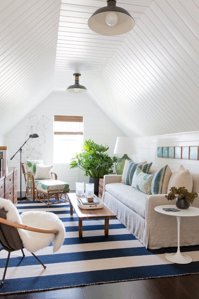 a living room filled with furniture and a blue and white striped rug on top of a hard wood floor