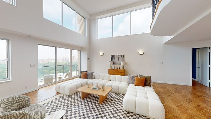 a large living room with high ceilings and floor to ceiling windows on the second floor