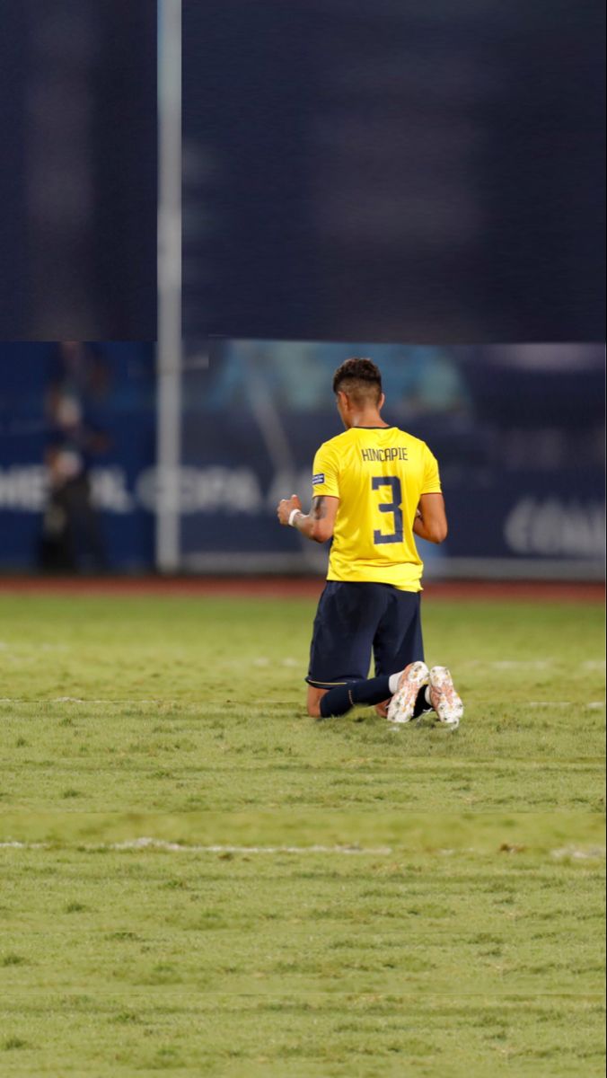 a young man in a yellow shirt standing on a soccer field