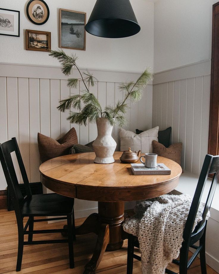 a table and chairs in a room with pictures on the wall above it, along with a potted plant