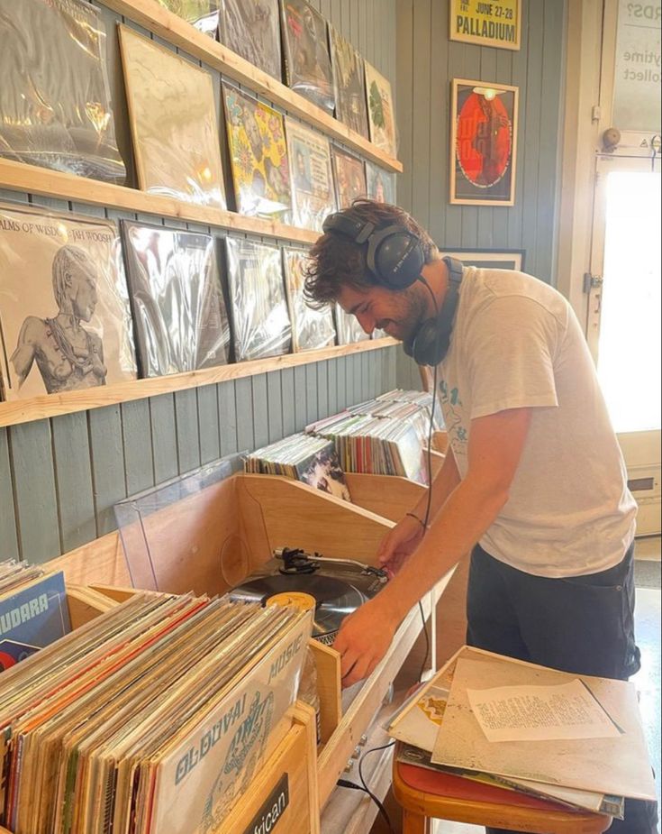 a man standing in front of a record shelf filled with records