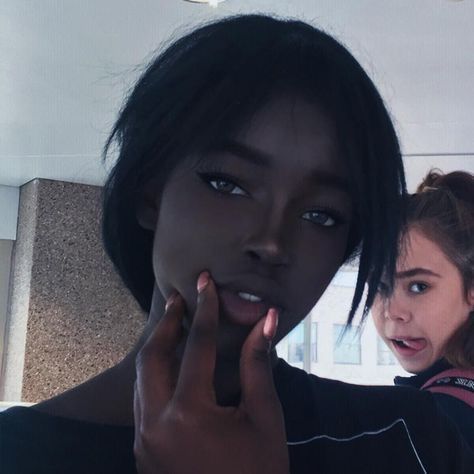 two women are posing for the camera with one holding her hand up to her face